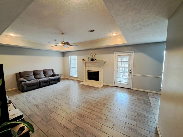 unfurnished living room with a raised ceiling, plenty of natural light, and a textured ceiling