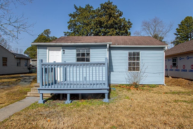 back of house with a wooden deck and a lawn