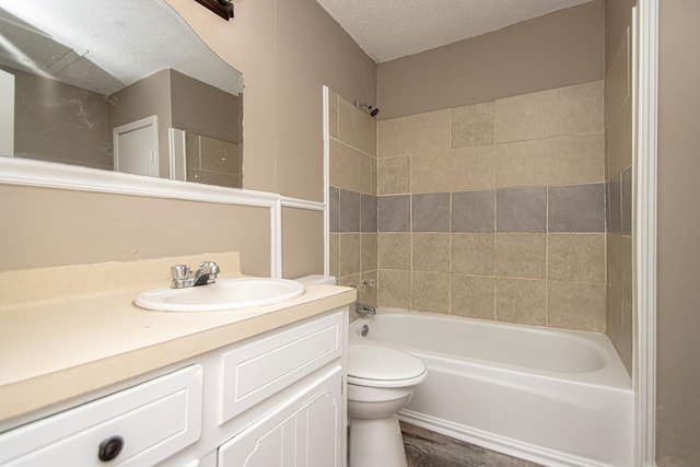 full bathroom with tiled shower / bath, vanity, a textured ceiling, and toilet