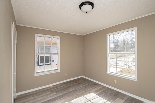 empty room with ornamental molding, a textured ceiling, and light wood-type flooring