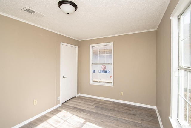 empty room featuring ornamental molding, light hardwood / wood-style floors, and a textured ceiling