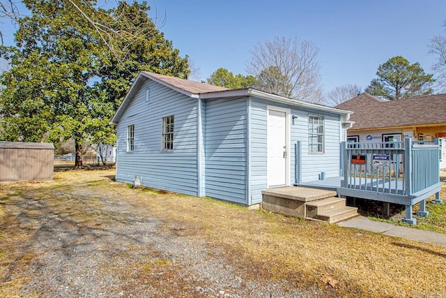 back of house with a lawn, an outdoor structure, and a deck