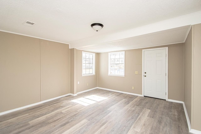 unfurnished room featuring ornamental molding, a textured ceiling, and light wood-type flooring