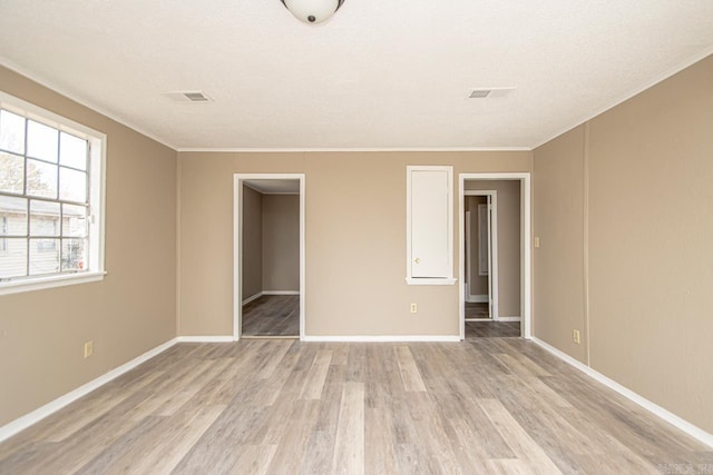 unfurnished bedroom featuring a closet, ornamental molding, light hardwood / wood-style flooring, and a textured ceiling