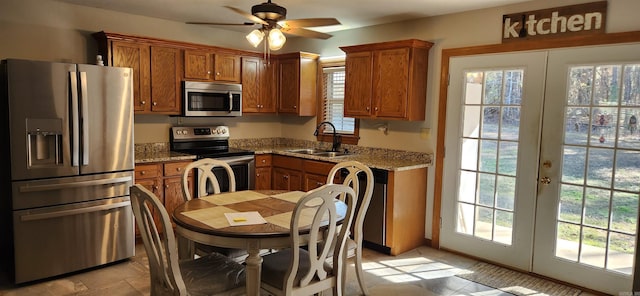 kitchen with french doors, appliances with stainless steel finishes, sink, and light stone counters