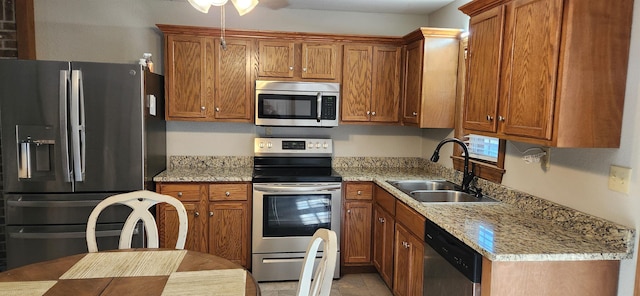 kitchen with light stone counters, ceiling fan, stainless steel appliances, and sink