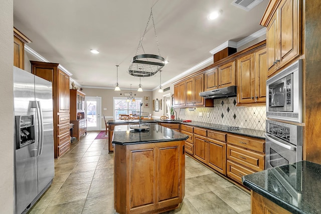 kitchen featuring under cabinet range hood, stainless steel appliances, a peninsula, visible vents, and backsplash