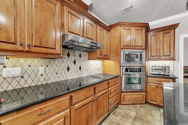 kitchen with a toaster, visible vents, dark stone counters, stainless steel appliances, and under cabinet range hood