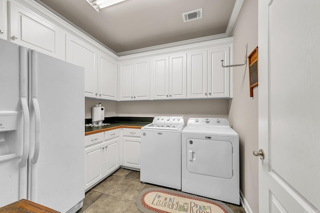 laundry area featuring cabinet space, light tile patterned floors, visible vents, and washing machine and clothes dryer