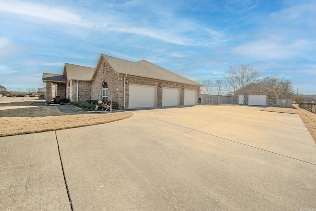 view of side of home featuring a garage, brick siding, a shingled roof, and fence