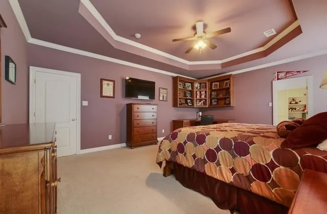 bedroom with a tray ceiling, light carpet, and crown molding