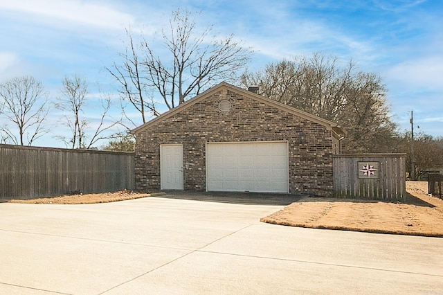 view of front facade featuring brick siding, driveway, an outdoor structure, and fence