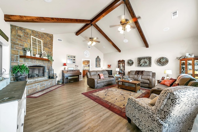 living room featuring high vaulted ceiling, a fireplace, wood finished floors, and visible vents