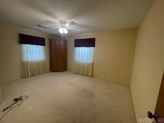 carpeted spare room featuring a wealth of natural light, a textured ceiling, and ceiling fan