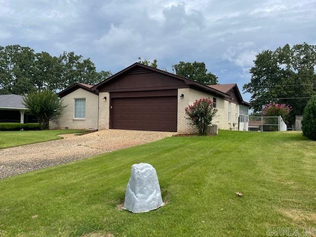 ranch-style home featuring a garage and a front lawn