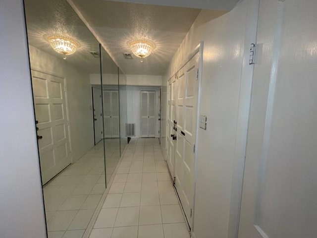 corridor featuring light tile patterned floors and a textured ceiling