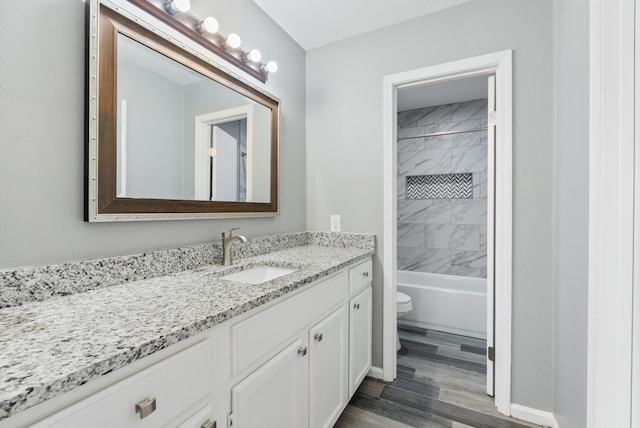 full bathroom featuring tiled shower / bath combo, vanity, wood-type flooring, and toilet