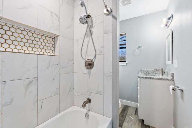 bathroom featuring vanity, tiled shower / bath combo, and wood-type flooring