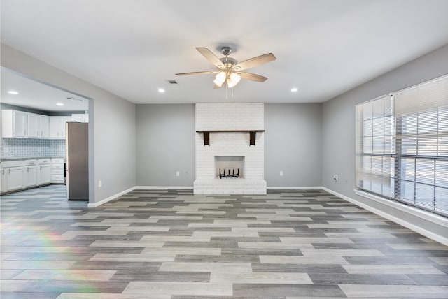 unfurnished living room featuring a fireplace, ceiling fan, and light wood-type flooring