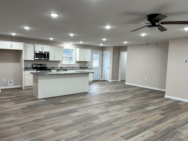 kitchen with a kitchen island, appliances with stainless steel finishes, sink, white cabinets, and light hardwood / wood-style floors