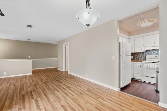 kitchen with white cabinetry, tasteful backsplash, hanging light fixtures, light wood-type flooring, and white appliances