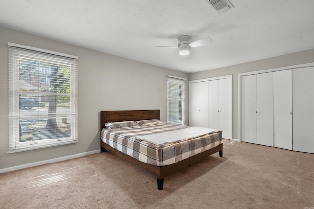 carpeted bedroom with multiple closets and ceiling fan