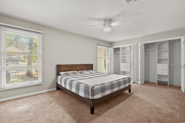 carpeted bedroom featuring multiple closets and ceiling fan