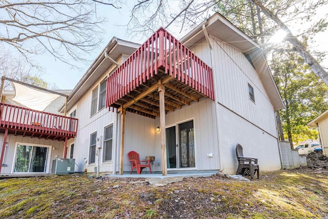 back of property with a wooden deck, a patio, and central air condition unit