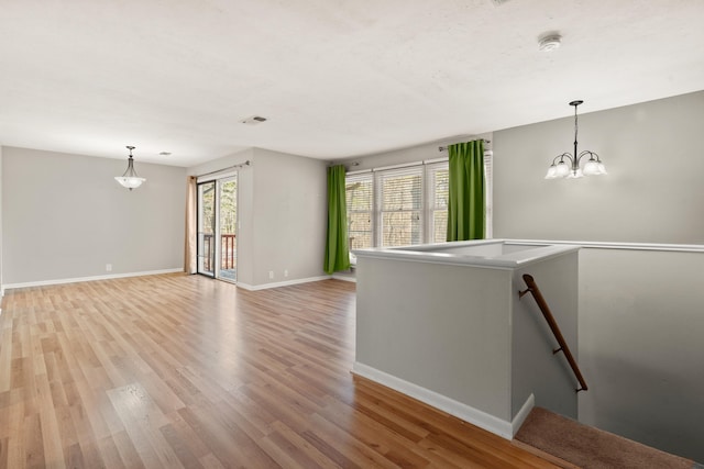 empty room with a chandelier and light wood-type flooring