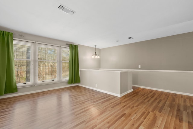 spare room featuring an inviting chandelier and light hardwood / wood-style floors