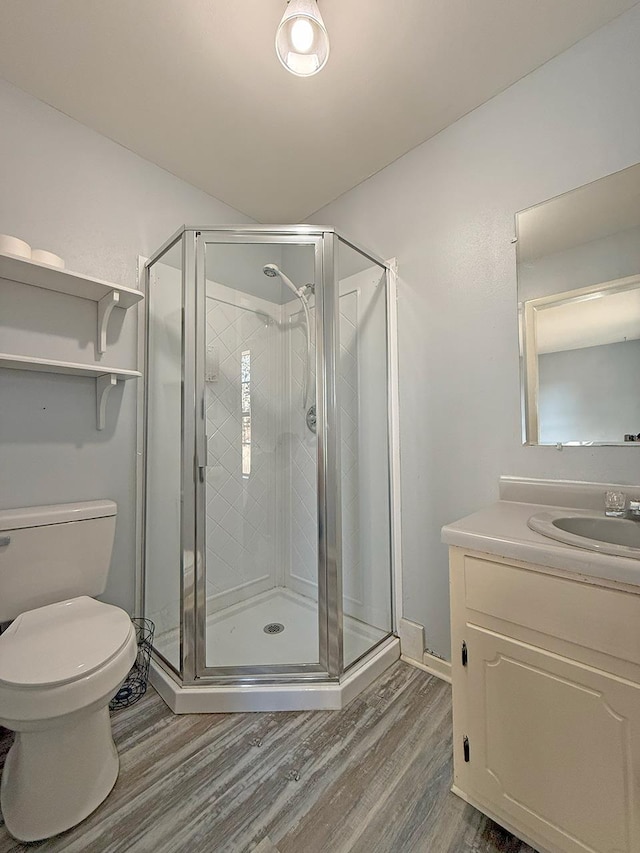 bathroom with an enclosed shower, vanity, wood-type flooring, and toilet