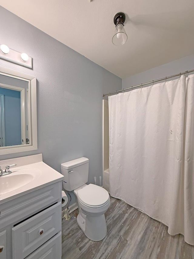 full bathroom featuring wood-type flooring, shower / tub combo, vanity, and toilet