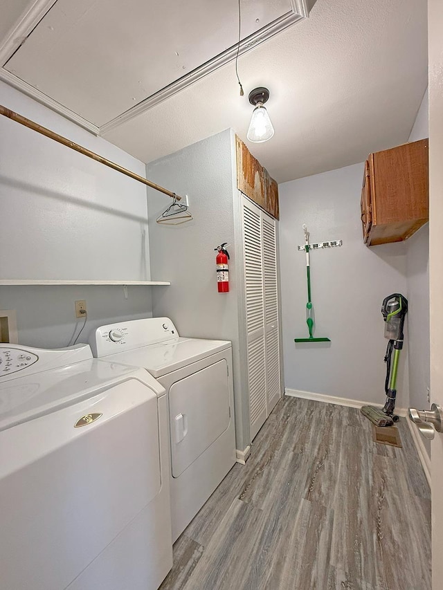 laundry room with cabinets, light hardwood / wood-style floors, washer and dryer, and a textured ceiling