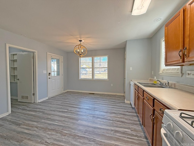 kitchen featuring decorative light fixtures, sink, hardwood / wood-style flooring, white appliances, and an inviting chandelier