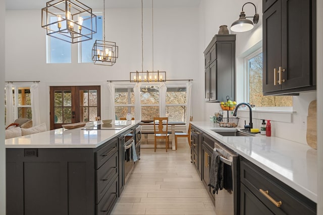 kitchen featuring pendant lighting, sink, dishwasher, a kitchen island, and a chandelier