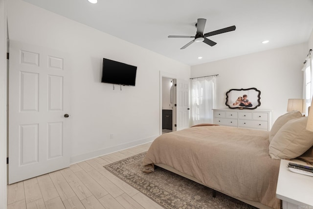 bedroom featuring multiple windows, ensuite bathroom, ceiling fan, and light hardwood / wood-style floors