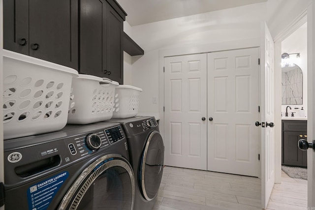 washroom featuring cabinets, separate washer and dryer, sink, and light hardwood / wood-style flooring