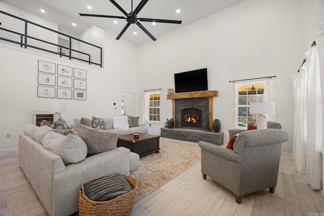 living room with a high ceiling, a fireplace, and light hardwood / wood-style flooring