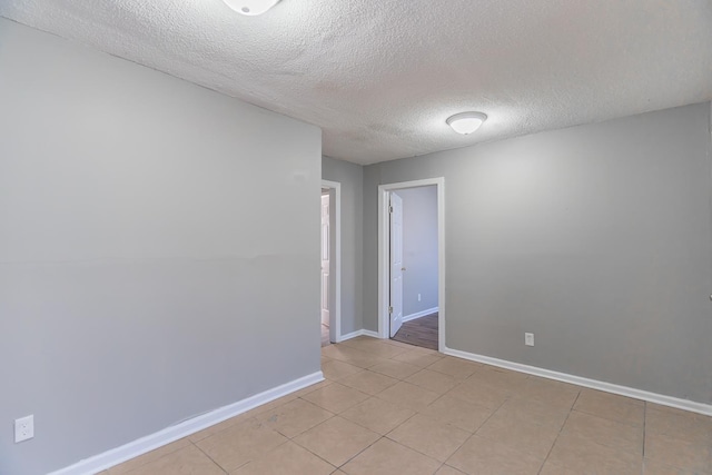 tiled empty room featuring a textured ceiling