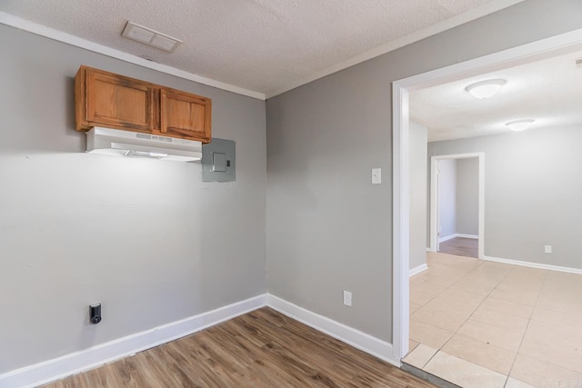 unfurnished room with electric panel, light hardwood / wood-style floors, and a textured ceiling