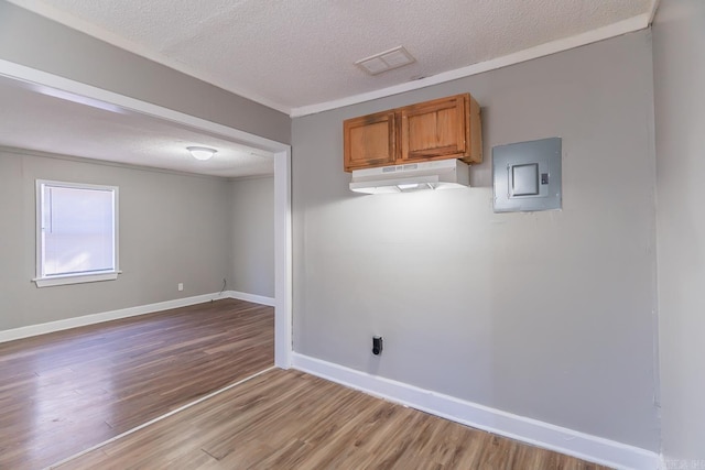 spare room featuring hardwood / wood-style floors, electric panel, and a textured ceiling