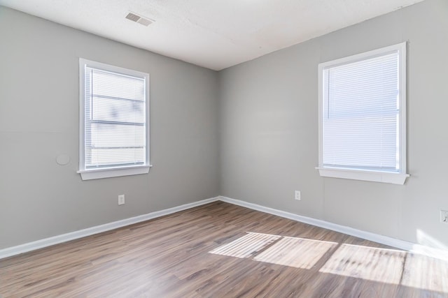 unfurnished room with a textured ceiling and light hardwood / wood-style floors