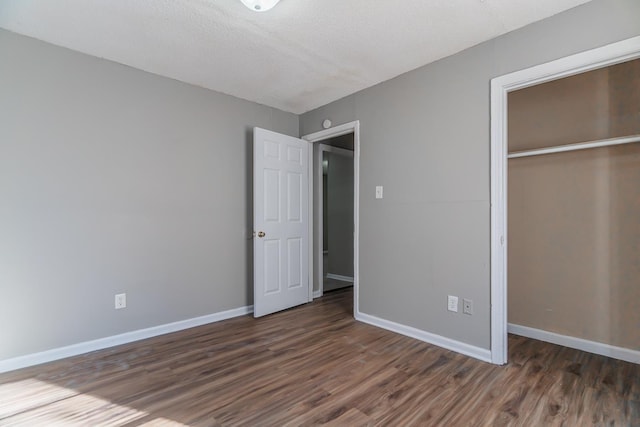 unfurnished bedroom featuring dark hardwood / wood-style floors, a textured ceiling, and a closet