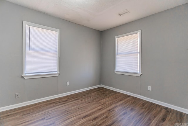 unfurnished room with dark wood-type flooring, plenty of natural light, and a textured ceiling