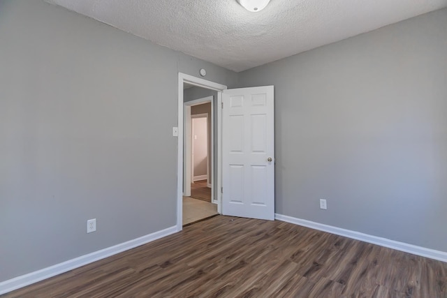 unfurnished room with dark hardwood / wood-style flooring and a textured ceiling