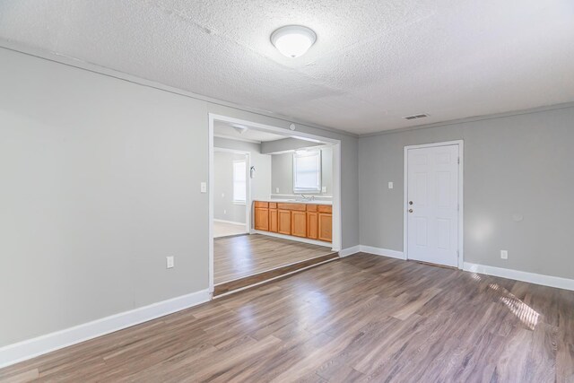 empty room with hardwood / wood-style floors, sink, and a textured ceiling