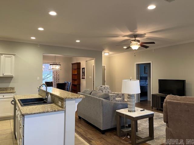 living room featuring ornamental molding, sink, ceiling fan, and light wood-type flooring