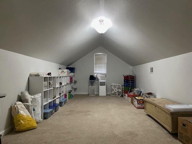 interior space featuring light colored carpet, vaulted ceiling, and a textured ceiling