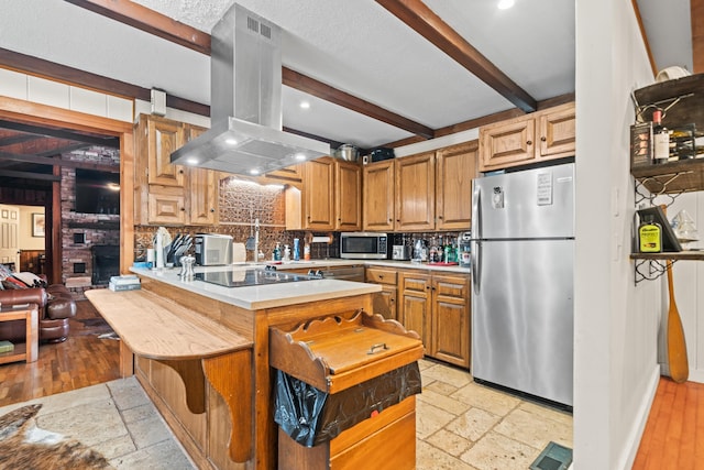 kitchen featuring appliances with stainless steel finishes, beamed ceiling, a kitchen bar, island exhaust hood, and kitchen peninsula