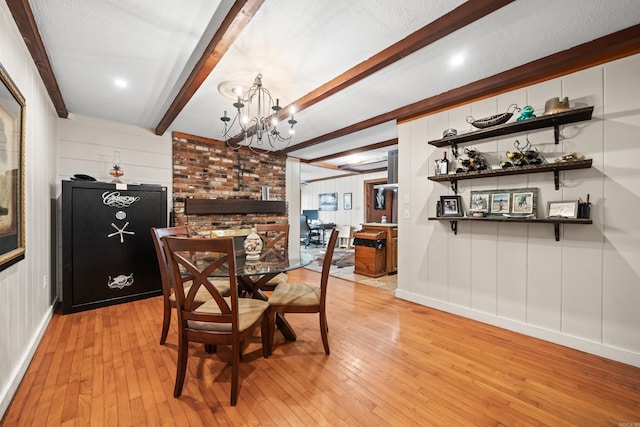 dining area featuring beamed ceiling, a textured ceiling, a notable chandelier, and light hardwood / wood-style floors